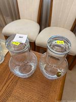 Pair of crystal carafes with matching glass tumblers on wooden table with chairs in background