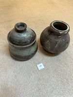 Pair of rustic ceramic jars on carpeted floor showing overall shapes and glaze finish.