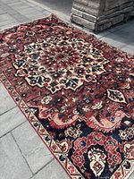 Full view of handmade Bakhtiari Persian rug laid outdoors on paved ground showing colors and overall pattern.