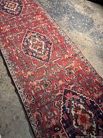 Full view of a long Hamadan runner rug on concrete floor showing detailed pattern and color