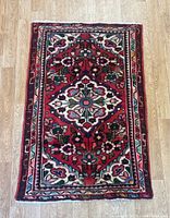 Full top view of the small rectangular Lilian rug showing a detailed floral medallion and border pattern with red, blue, green, and cream tones.