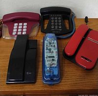 Group of five vintage corded telephones on wooden surface