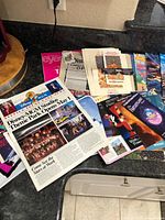 Countertop view of assorted Disney newsletters, brochures and passes including Disney-MGM Studios opening newspaper