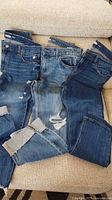Three pairs of jeans laid out showing washes and distressing