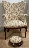 Front view of armchair and footstool showing overall design, upholstery and wood finish