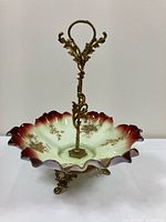 Front view showing entire compote with ornate brass handle and ruffled glass bowl