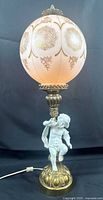 Full view of lamp showing globe shade, column, cherub base and cord