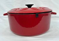 Side view of red enamel Dutch oven with lid on