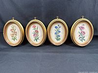 All four oval framed flower needlepoints front view
