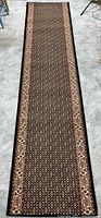 Full length view of dark patterned hallway runner rug on light floor
