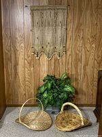 Overall lot showing wall hanging, two wicker baskets and faux greenery