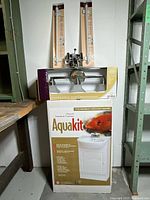 Front view of boxed Aquakit vanity with faucet and accessory set on top
