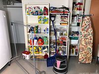 wide view of shelving with cleaning products, shovel, garment rack, exercise step and ironing board