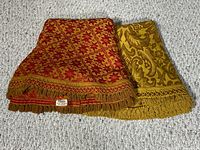 Both folded tablecloths showing patterns and fringe