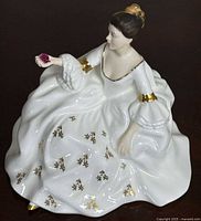 Full view of figurine showing seated woman in white dress with gold accents