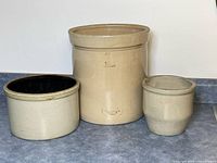 Three beige crocks side by side on counter
