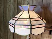 Full view of stained glass pendant lamp against wood panel background