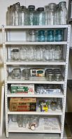 Full shelving unit with assorted jars, boxes of Bernardin lids
