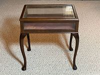 Angled full view of wood display case table showing glass sides and cabriole legs