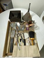 Full lot overview showing funnel, cherry pitter, pans, measuring cups, canvas roll with scissors and accessories