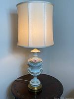 Full view of lit porcelain lamp with fabric shade