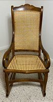 Front view of wood rocking chair showing cane seat and back