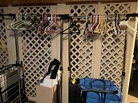 Full view of three garment racks with hangers and other items around them