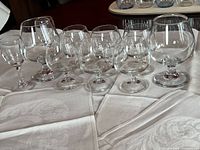 Group of clear stemmed glasses on tablecloth