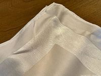 Close view of hemmed corner of ivory damask linen