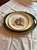 Three nested ceramic pieces: handled green tray, cream oval platter, round turkey platter