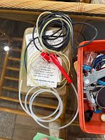 Airbrush accessory tubing and micro spray tool with red handle shown on a glass table.