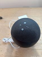 Top view of the Amazon Echo 4th Generation smart speaker showing control buttons and connected power cable.