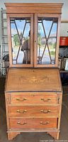 Front view of the Edwardian mahogany bureau bookcase showing marquetry fall front, brass handles, glazed upper cabinet doors with astragal bars, and moulded cornice.