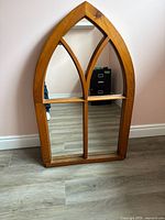 Front view of the arched wooden windowpane style mirror showing the natural wood frame and divided glass sections.