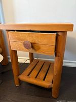 Front view of solid cedar night stand showing the drawer with round wooden knob and three cylindrical legs.