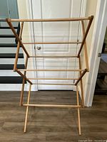 Tall wood drying rack with multiple horizontal bars standing on the floor