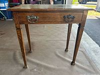 Front view of the antique wooden entrance table showing wood grain, drawer, and leg design.
