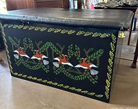 Side view showing hand painted birds and leaf border on wooden chest.