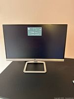 Front view of HP 23 inch monitor powered on showing HP logo and model information on screen.