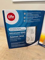 Life Brand Advanced TENS unit box detailing features like electrical nerve stimulation and muscle stimulation for pain relief therapy.