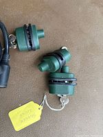 Three green trigger locks on a brown surface with one key attached to a yellow tag marked 'Trigger Locks'.