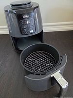 Ninja Air Fryer open showing basket with metal rack inside, control panel above basket.