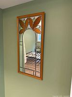 Full view of the rectangular mirror with wooden frame and stained glass flower design at top.