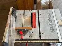 Top-down view of Craftsman table saw showcasing metal tabletop, blade throat plate, fence and Craftsman logo
