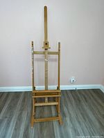 Front view of the wooden easel standing upright, showing adjustable center mast and base.