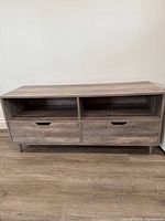 Front view of the TV stand showing two drawers and two open cubbies beneath a rectangular wooden top.