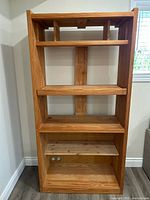 Full front view of the solid wood entertainment unit showing three shelves and bottom storage compartment with two white knobs.