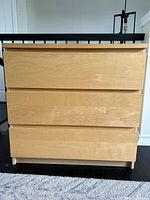 Front view of the three drawer wood laminate dresser showing drawer fronts and general condition.