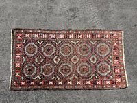 Full flat lay of the Persian style rug showing complete geometric pattern and border details in natural light, emphasizing colors and wear.