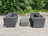 Two resin wicker loveseats and two square wicker tables arranged outdoors